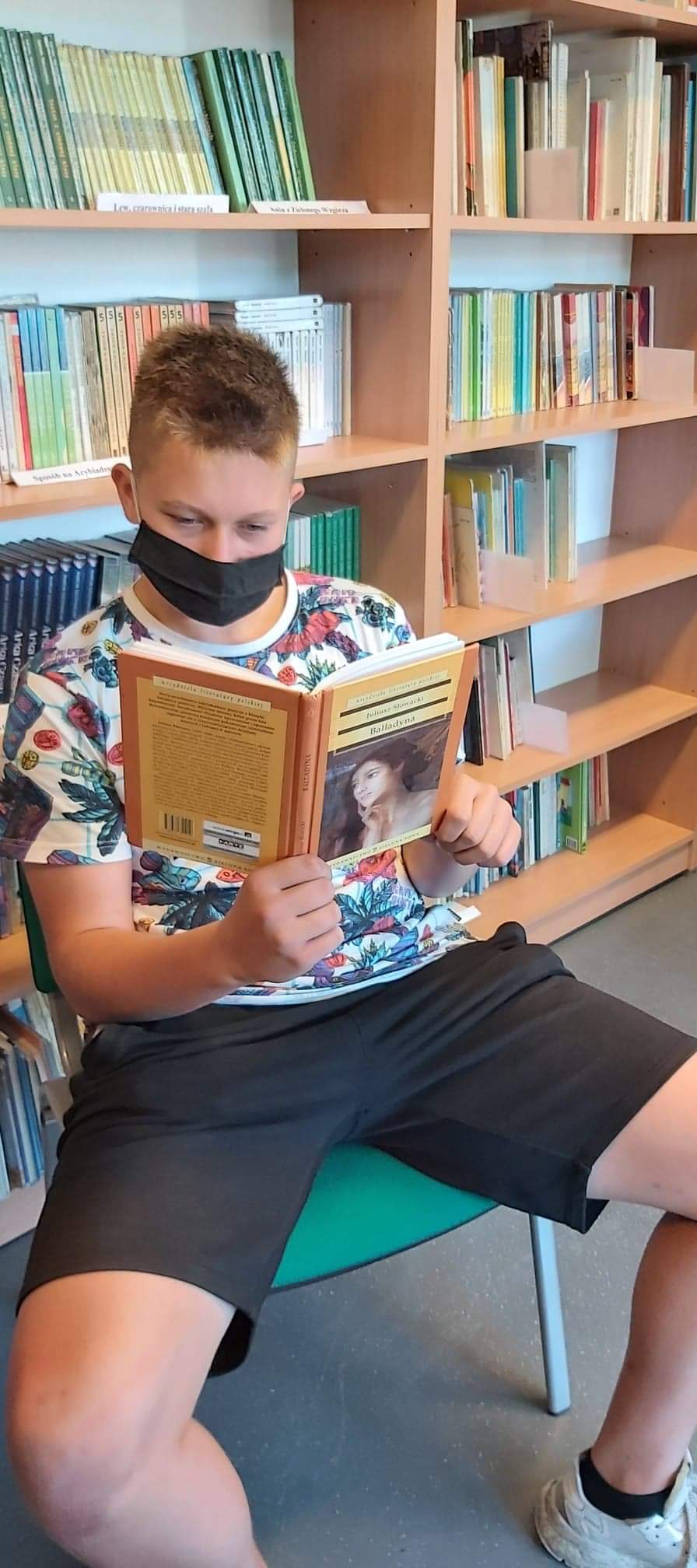 Zdjęcie przedstawiające chłopaka czytającego Balladynę w bibliotece